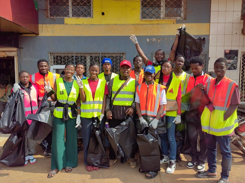 Éco-bénévoles en gilets réfléchissants, sacs de collecte en main, au point de départ de l'Opération Quartier Propre près de Yoyo-Bar, Cité Verte, Yaoundé II
